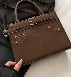 Detail van de donkerbruine leren tas met zilveren studs en decoratieve gesp