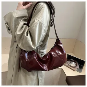 Detail of burgundy glossy underarm bag showing patent leather texture and pleated design