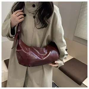 Detail of burgundy hobo bag with glossy leather texture and stylish knot shoulder strap