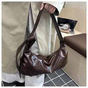 Detail of a dark brown glossy underarm bag featuring a stylish knotted shoulder strap