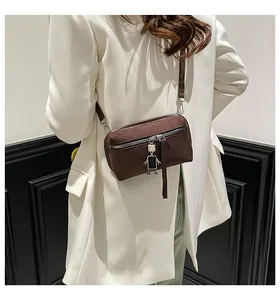 Detail of dark brown crossbody box bag featuring a unique silver robot zipper pendant