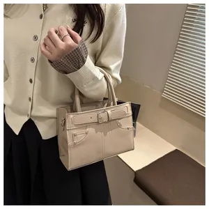 Detail of beige PU leather tote bag featuring decorative buckles and metal rivet accents