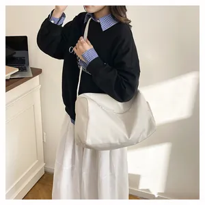 Detail view of the white travel bag with adjustable strap worn by a model in casual style