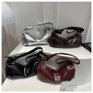 Detail of minimalist leather shoulder bags in silver, brown, black and burgundy with knot strap