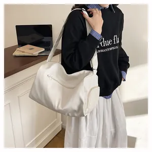 Close-up of white travel tote bag with functional side zippers and wide shoulder straps