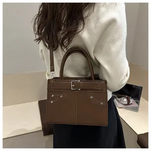 Detail of dark coffee vintage tote bag with metal rivets and decorative leather buckle