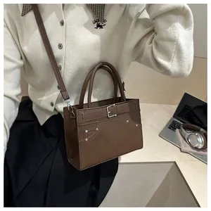 Close-up of vintage brown leather tote bag with metal buckles and rivet details