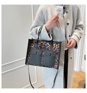 Détail du sac cabas léopard avec poches en cuir noir porté sur un manteau en laine