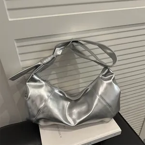 Metallic silver minimalist crescent shoulder bag with knot detail on the strap