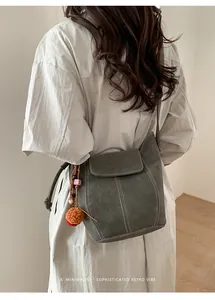 Détail du sac seau gris foncé minimaliste avec coutures contrastées et pompon décoratif
