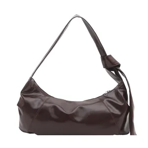 Chocolate hobo shoulder bag with glossy finish and large knot detail on strap