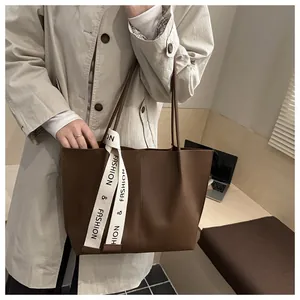 Close-up of brown PU leather tote bag featuring a decorative fashion letter ribbon strap