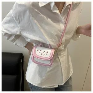 Detail of pink and white crossbody bag featuring cherry print and gold-tone metal buckle