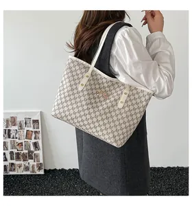 Dettaglio della grande borsa tote con motivo M marrone, manici in pelle bianca e fibbia a fiocco