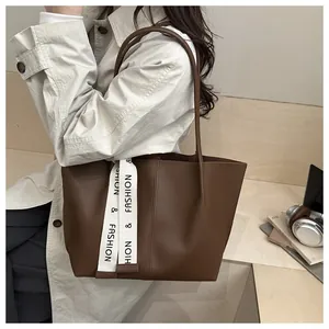 Brown leather tote bag with stylish logo strap and slim straps for daily commute