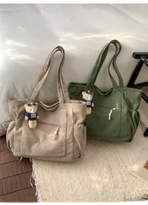 Detail of corduroy tote bags with plush bear pendants in khaki and olive green