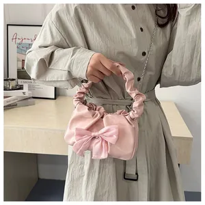 Détail du sac à main plissé rose avec un grand nœud en satin et une bandoulière en chaîne