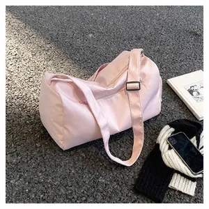 Detailed close-up of pink nylon travel bag with adjustable strap on outdoor ground