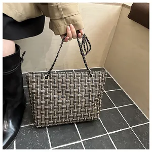 Detail van tweed textuur en gouden kettingriem op stijlvolle driekleurige tas