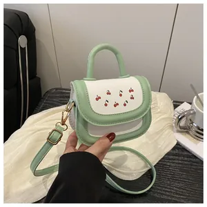 Detail of mint green and white crossbody bag with cherry print and golden hardware