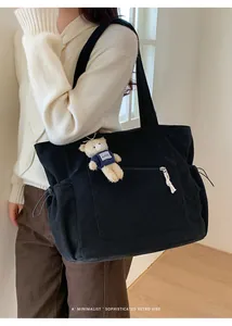 Detail of black corduroy tote bag showing side drawstring pockets and plush bear charm