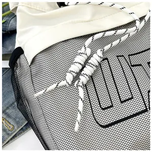 Detail of modern tote bag with white fabric and black mesh featuring OUT lettering decoration