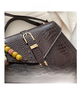 Detail shot of a dark brown crocodile texture bag with gold hardware and colorful beads