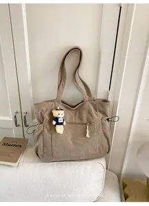 Close-up of khaki corduroy tote bag with front zipper pocket and cute bear charm