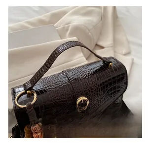 Detailed view of dark brown faux leather bag with crocodile texture and beaded charm