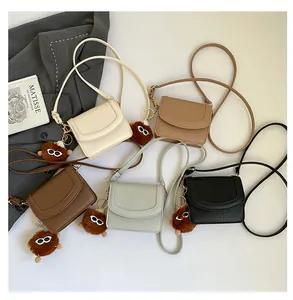 Flat lay of mini textured leather flap bags in five colors with plush ball charms