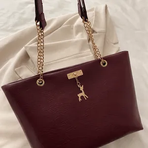Détail du sac cabas bordeaux avec pendentif cerf doré et poignée en chaîne sur tissu