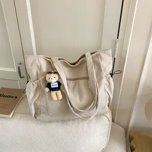 Minimalist beige corduroy tote bag with side pockets and a cute bear keychain charm