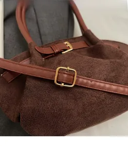 Detailweergave van de bruine suède handtas met gouden metalen gesp en lederen riem