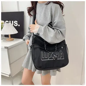 Detail of black tote bag with white WIRA lettering and wide shoulder strap