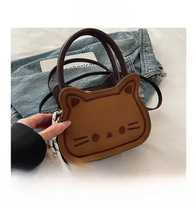 Detail of a brown suede cat-shaped handbag with leather handles and decorative silk scarf