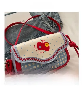 Close-up of blue polka dot flap and red apple design on a mini shoulder bag