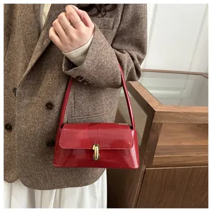 Detail of red patent leather baguette bag with a polished golden metal clasp