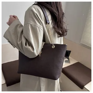 Detail of dark brown tote bag with metal chain strap and golden cat pendant charm