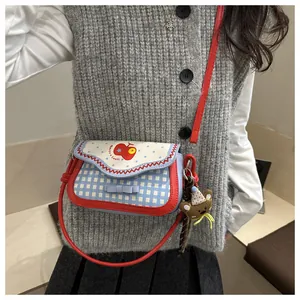 Detail of cute red apple pattern and blue bow on checkered crossbody bag for girls