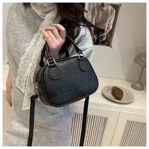 Detail of black leather Boston bag featuring embossed COIH'2DN letters and gold hardware