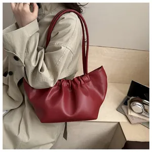 Deep red pleated tote bag worn with a beige trench coat for a stylish daily look