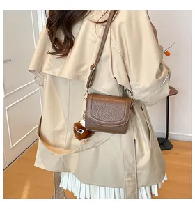 Detail of dark brown lychee texture crossbody bag with cute plush eye charm on strap