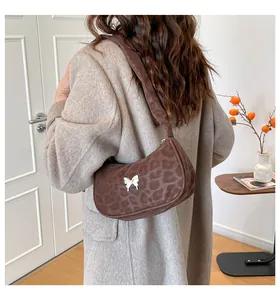 Detail of leopard print hobo bag with a silver butterfly accent shown on shoulder