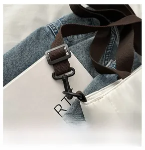 Détail de la bandoulière marron réglable avec crochet noir sur un sac fourre-tout matelassé