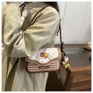 Close-up of apple pattern flap with wavy edges and brown checkered crossbody bag detail