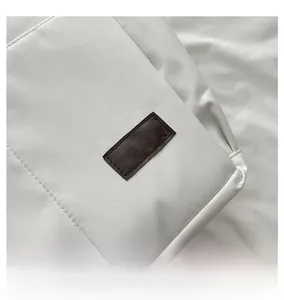 Détail de l'étiquette en cuir marron sur un sac fourre-tout blanc avec coutures soignées
