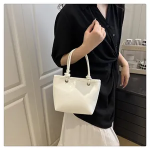 Detail van een minimalistische witte leren handtas met uniek geknoopt handvat