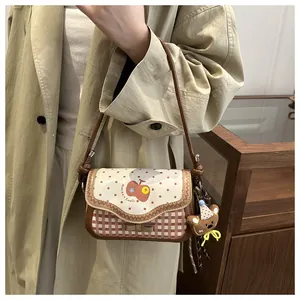 Detail view of pink apple shoulder bag with polka dots and teddy bear charm on model