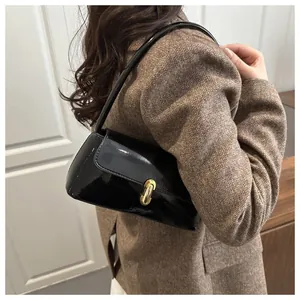 Detail of black glossy patent leather baguette bag with premium gold metallic buckle