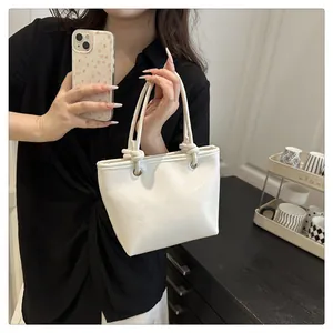 Detail van een minimalistische witte handtas met elegante touwknoop handvatten